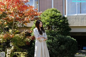 A woman in a yellow dress is walking in the grass.