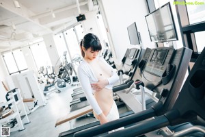 A naked woman standing in front of a gym machine.