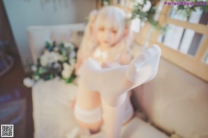 A woman laying on top of a bed wearing white stockings.