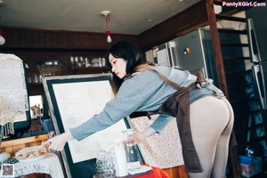 A woman standing behind a counter in a coffee shop.