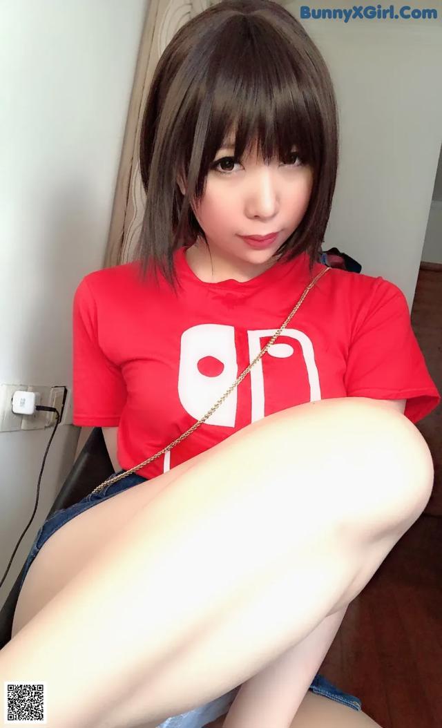 A woman in a red shirt is sitting on a chair.