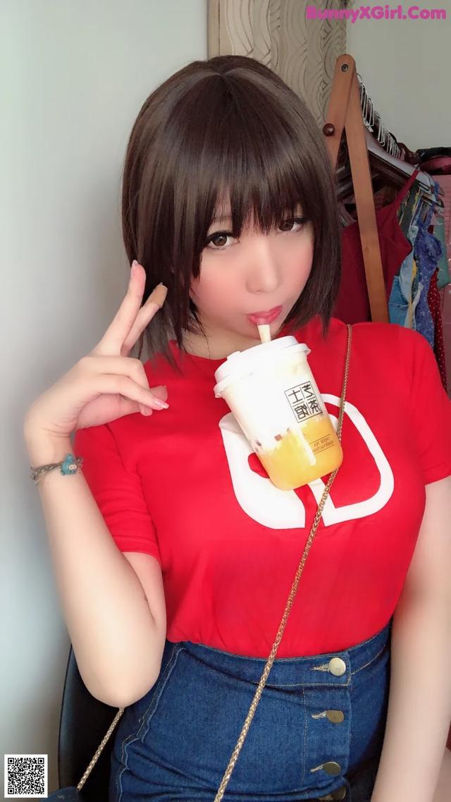 A woman in a red shirt holding a cup of orange juice.