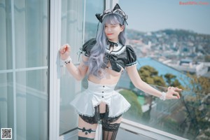 A woman in a maid outfit sitting on an orange chair.