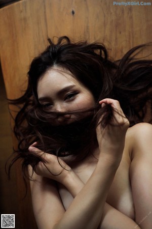 A naked woman laying on a black couch.