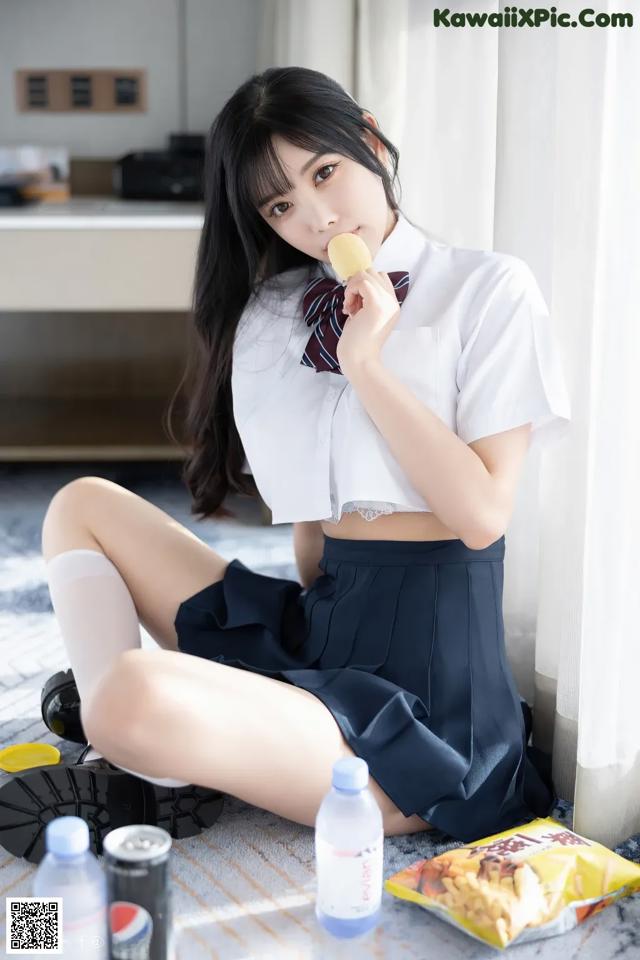 A woman in a school uniform eating a piece of food.