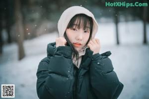 A woman wearing a black coat standing in the snow.