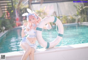 A woman in a bunny costume sitting by a pool.