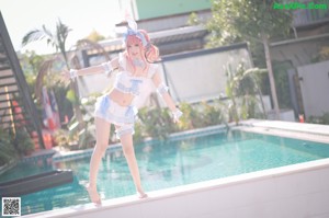 A woman in a bunny costume posing by a pool.