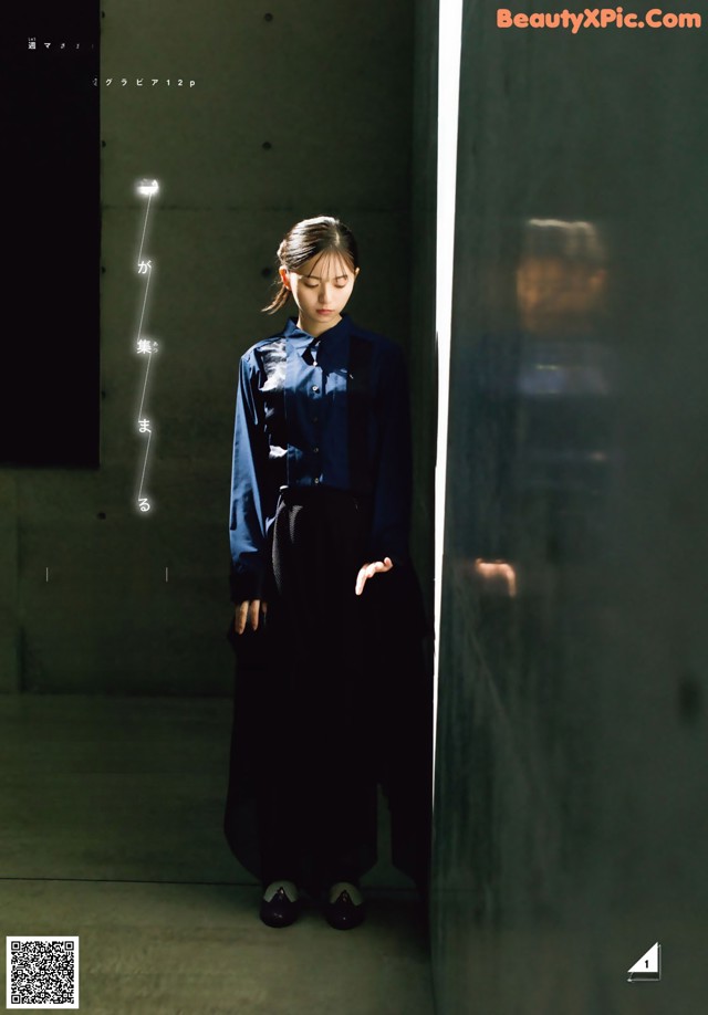 A woman standing in front of a wall in a dark room.