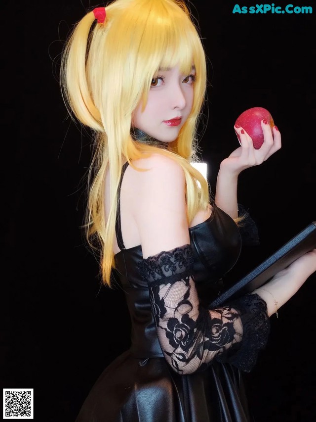 A woman in a black dress holding an apple.