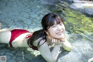 A woman in a red bikini laying on a rock.