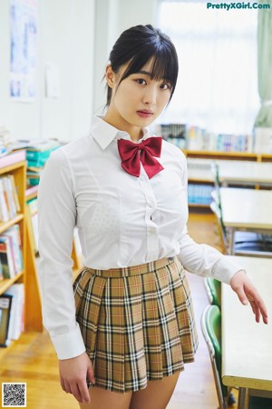 A woman in a school uniform sitting at a desk.