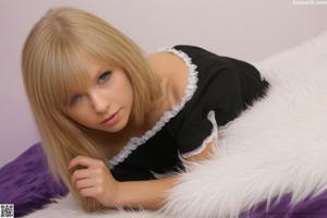 A woman with long blonde hair sitting on a couch.