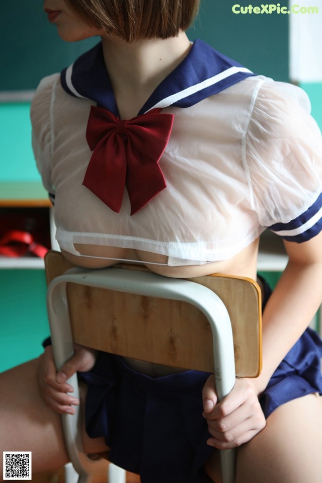 A woman in a school uniform sitting on a chair.