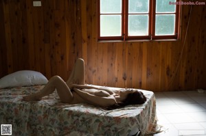 A naked woman laying on a bed with her hands on her breasts.