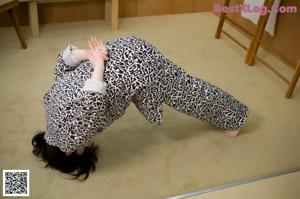 A woman in a leopard print shirt leaning against a wooden wall.