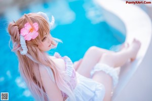 A woman in a bikini sitting on the edge of a swimming pool.