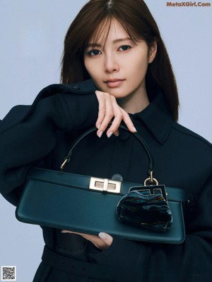 A woman in a blue dress holding a brown bag.