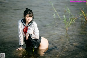 A woman in a sailor outfit is standing in the water.