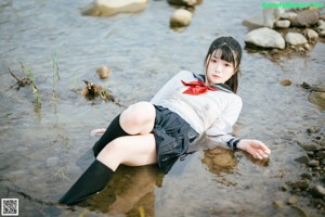 A woman in a sailor outfit sitting in the water.