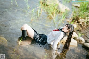A woman in a school uniform standing in the water.