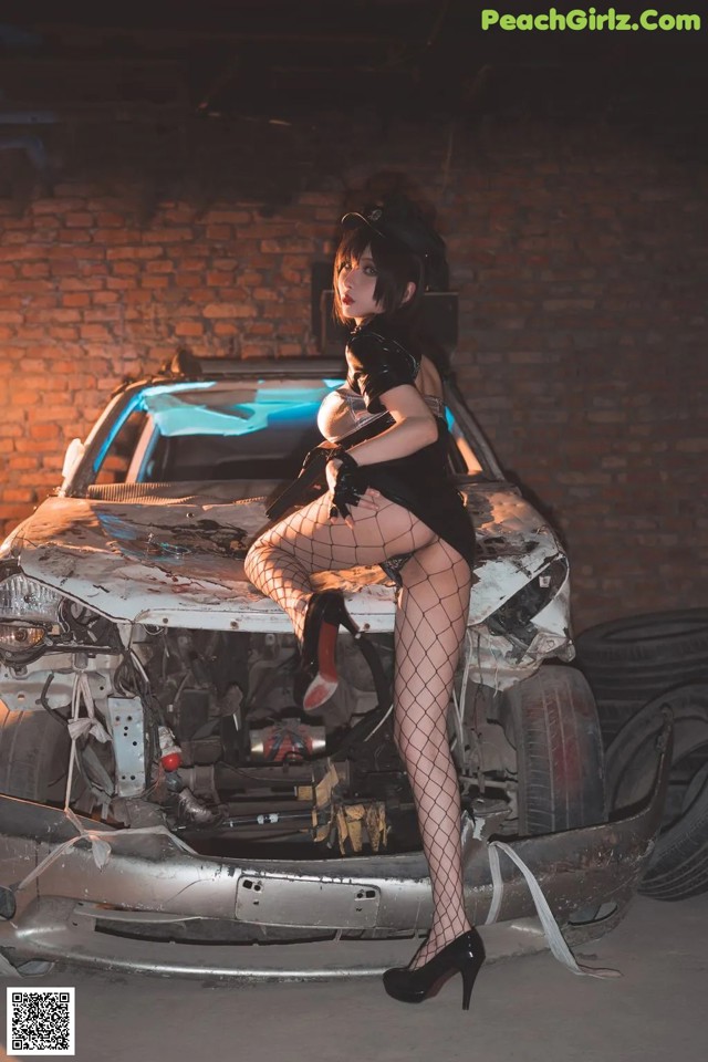 A woman sitting on top of a wrecked car.