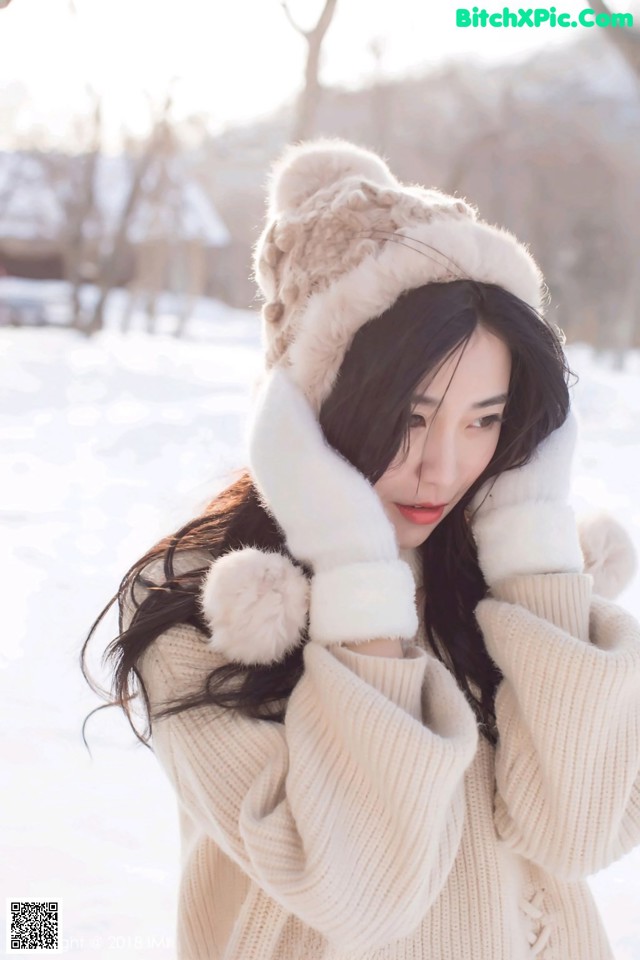 A woman wearing a white sweater and a furry hat.