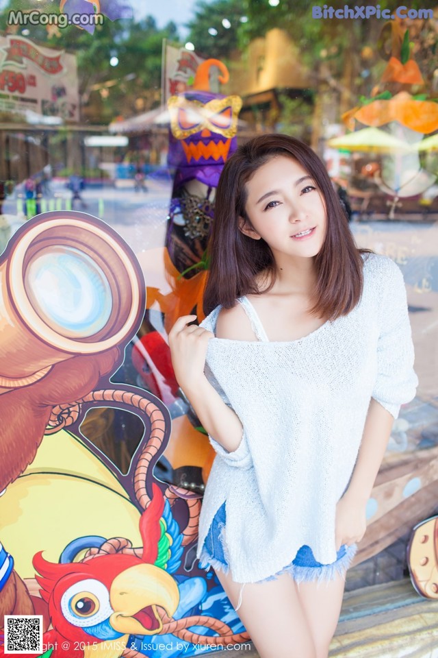 A woman standing in front of a carnival ride.