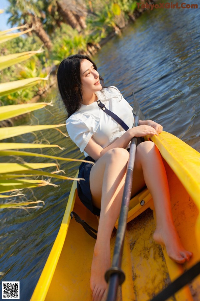 A woman sitting in a yellow canoe on the water.