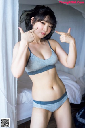 A woman in a gray bra top and blue panties posing for a picture.