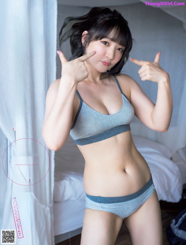 A woman in a gray bra top and blue panties posing for a picture.