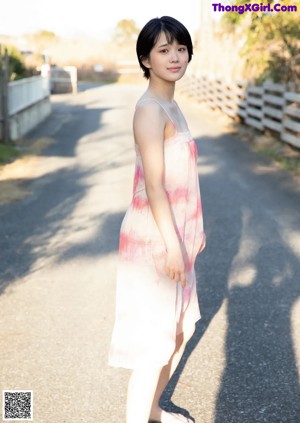 A woman in a white bikini standing on a road.