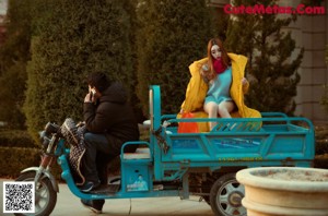 A woman in a yellow coat is posing for a picture.