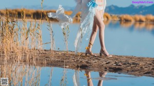 A woman in a white dress is standing in a field.