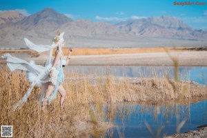 A woman in a blue bikini standing in a field.