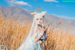 A woman in a white dress standing in a field of tall grass.