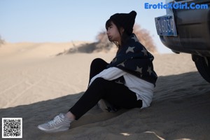 A little girl sitting on a wooden bench in a park.