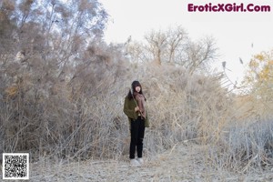 A woman sitting under a tree in the desert.