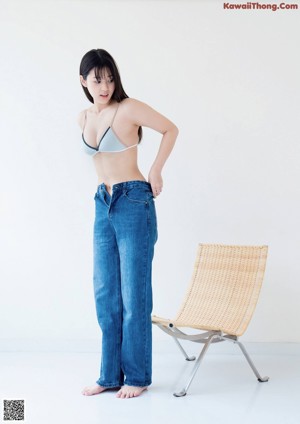 A woman in a blue bikini sitting on the floor next to a washing machine.