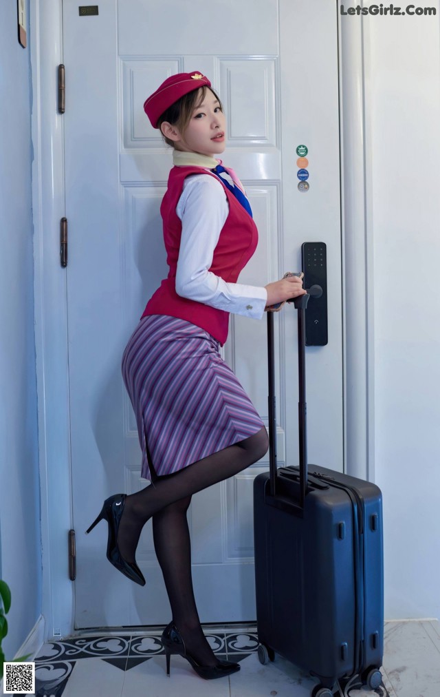 A woman in a red hat and striped skirt with a suitcase.