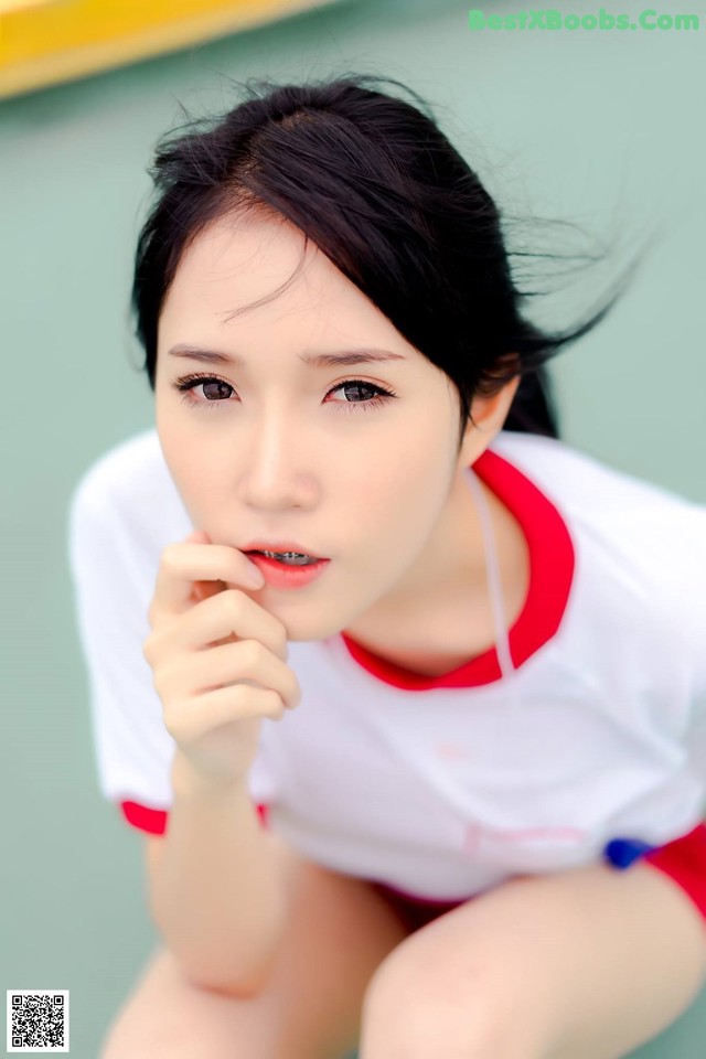 A woman in a white shirt and red shorts posing for a picture.