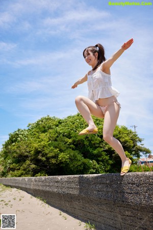 A naked asian woman standing in the grass holding a piece of meat.