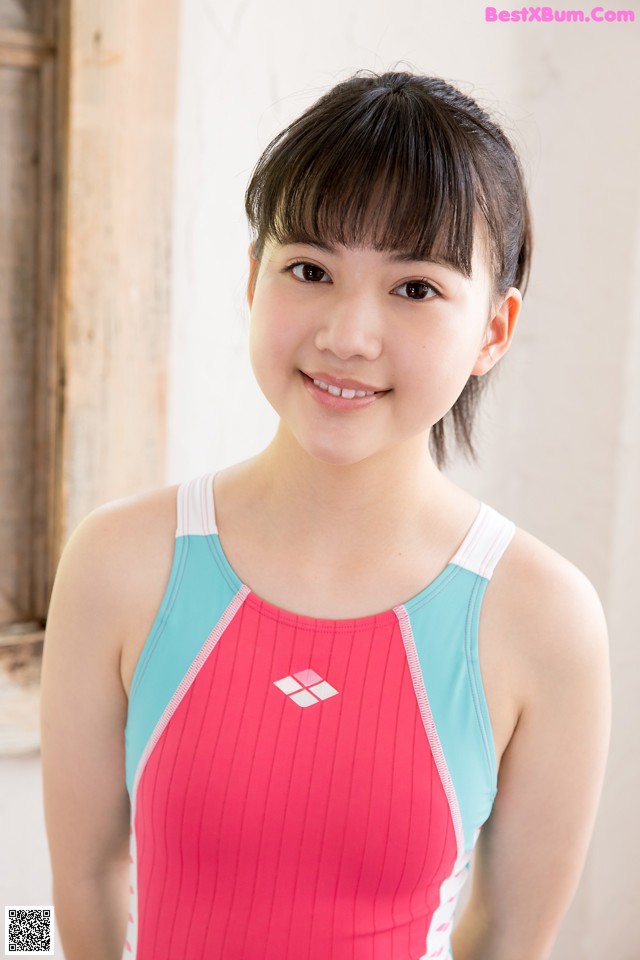 A young girl in a pink and blue swimsuit posing for a picture.