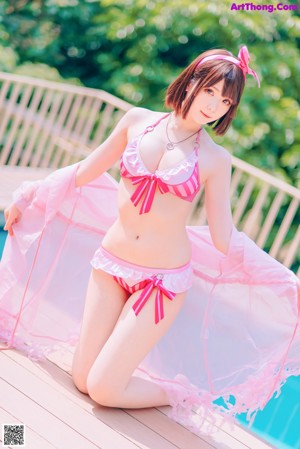 A woman in a pink bikini sitting on the edge of a pool.