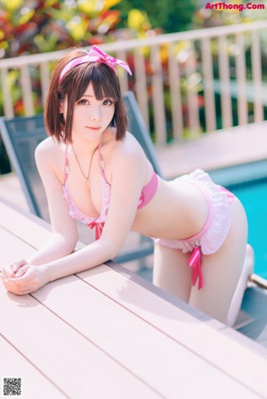A woman in a pink bikini standing next to a swimming pool.