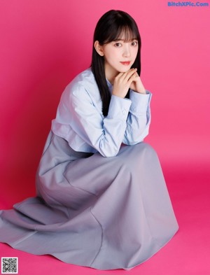 A woman standing in front of a pink wall.