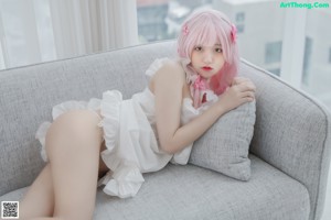 A woman with pink hair sitting on a couch.