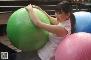 A woman in a pink tank top and blue shorts sitting on the floor.