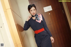 A woman in a blue uniform standing next to a toilet.