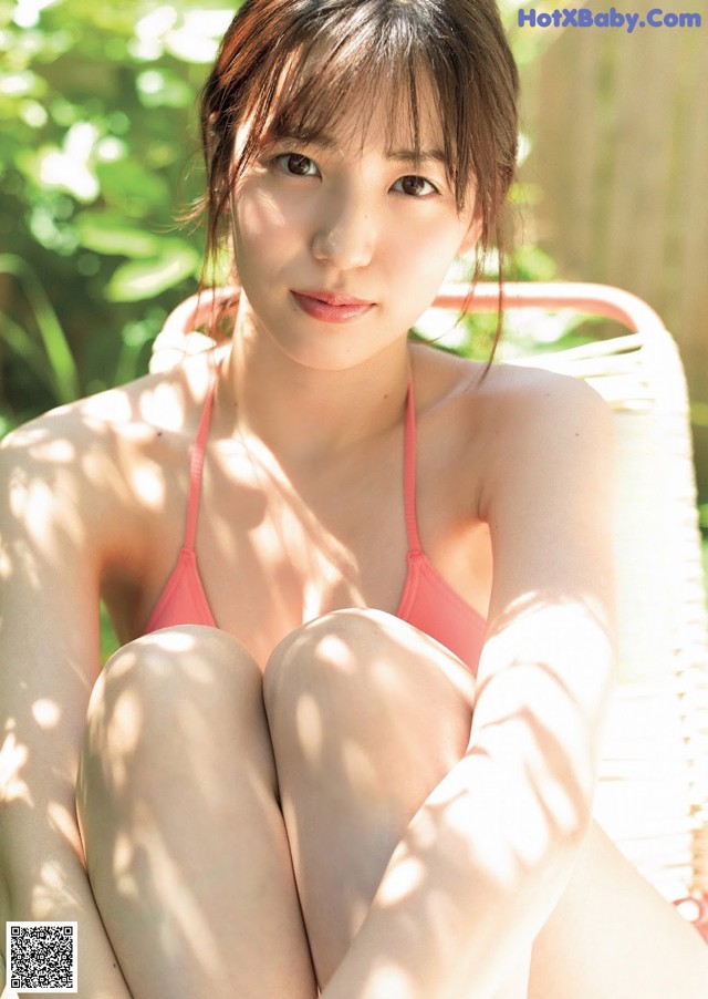 A woman in a pink bikini sitting on a white chair.